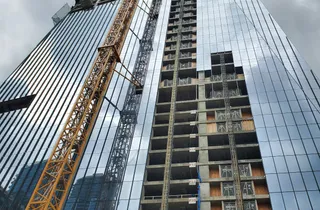 Ein Hochhaus im Bau mit einem Kran vor bewölktem Himmel.